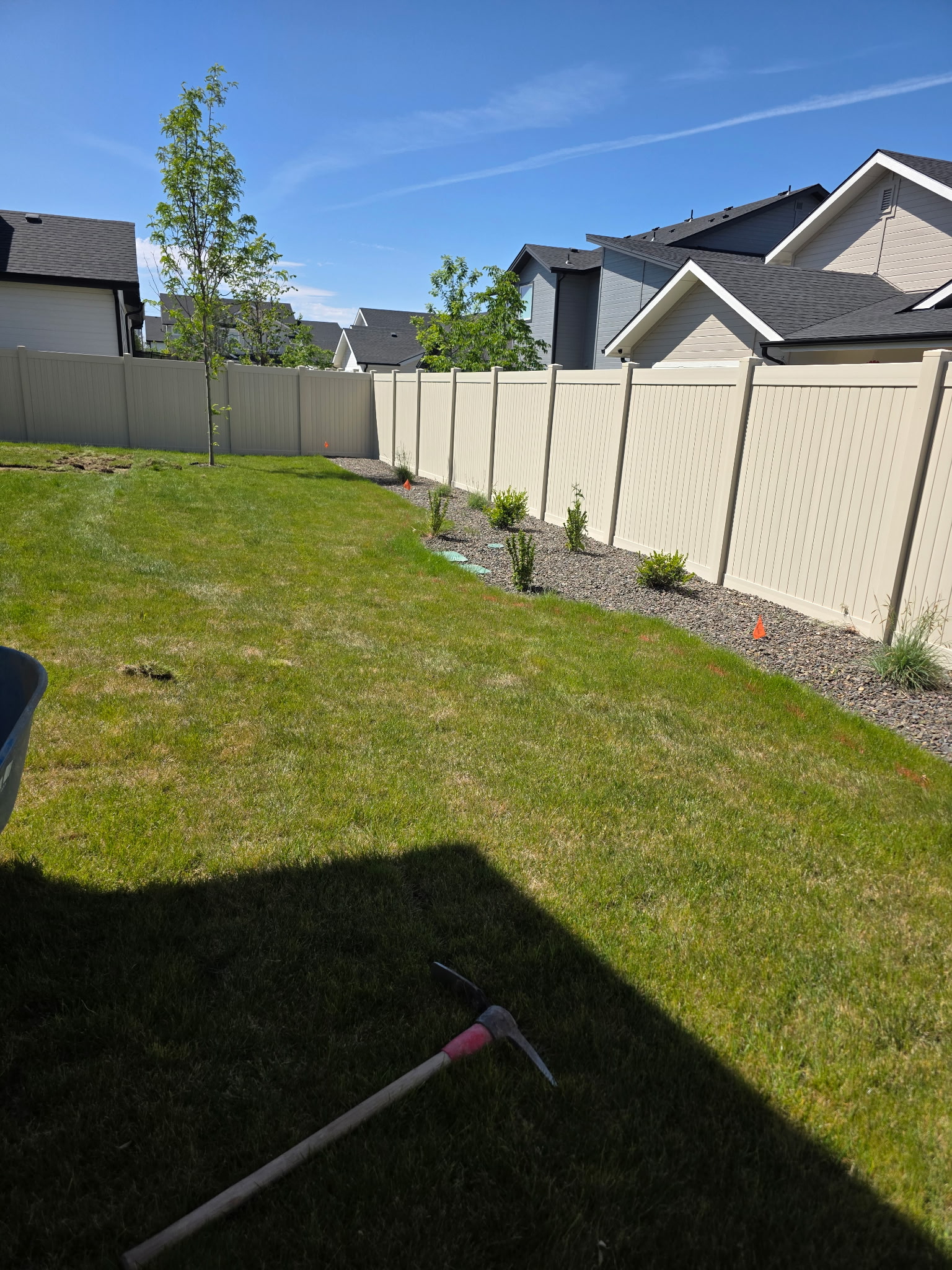 Original back yard lawn and planting bed along a white fence