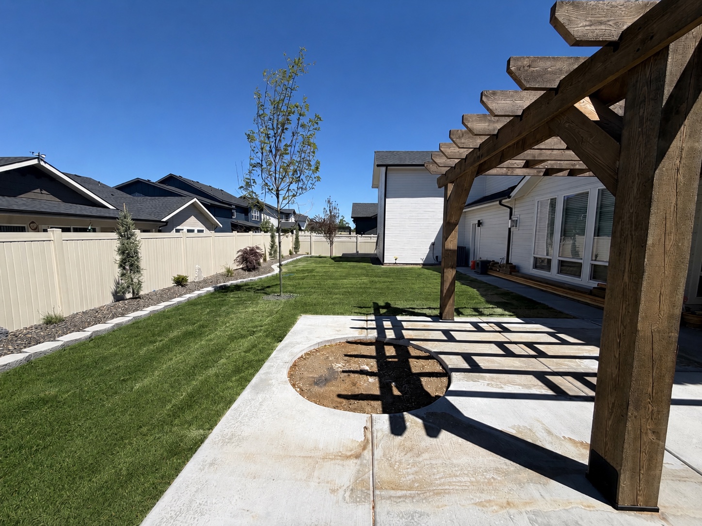 New pergola and concrete patio with the circular fire pit area prepared for installation