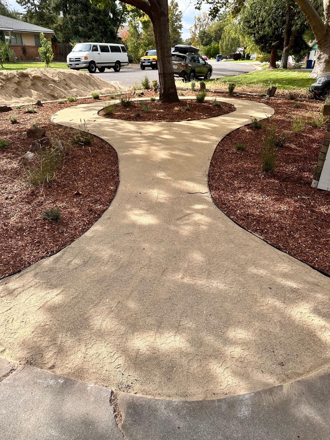 Front yard after revitalization with a curved walkway, fresh planting beds, and mulch