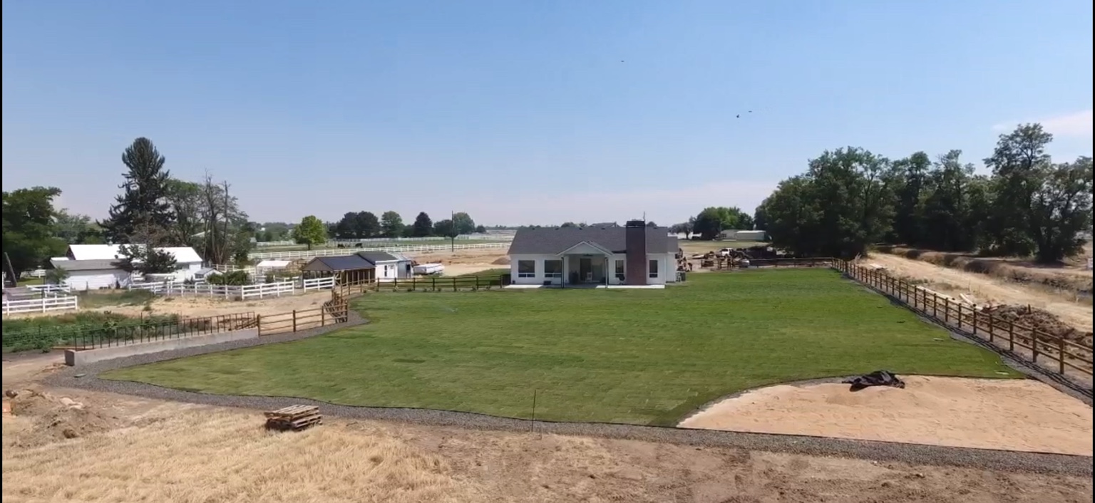 Kuna home after landscaping with an expansive green lawn and defined gravel border